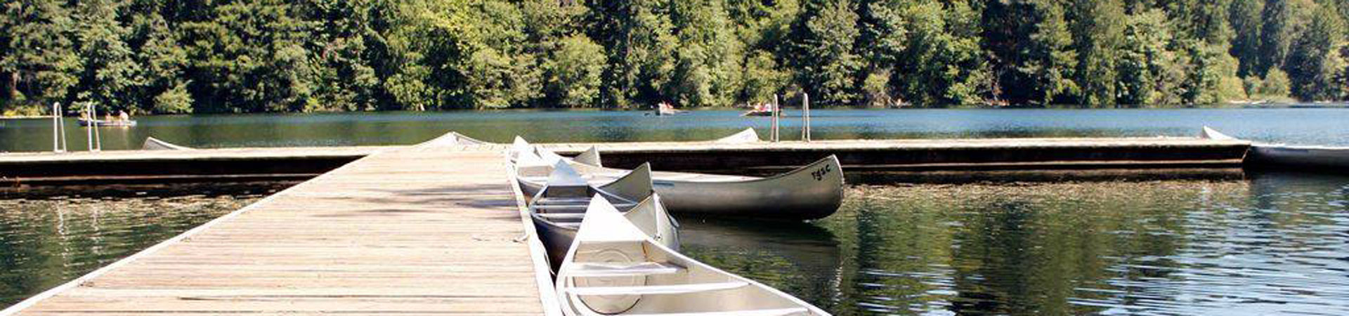  Two canoes next to a dock on a lake at Girl Scout camp. 