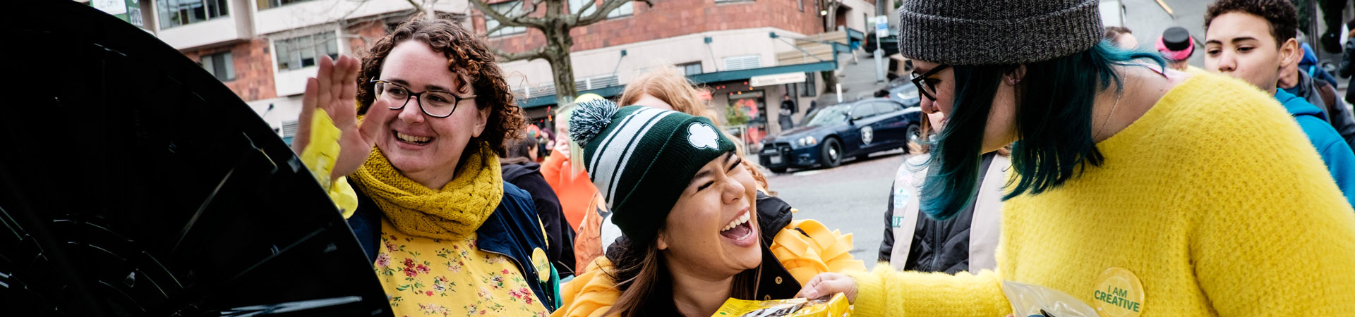  smiling Girl Scout staff dressed in matching yellow outfits attend a cookie parade. 