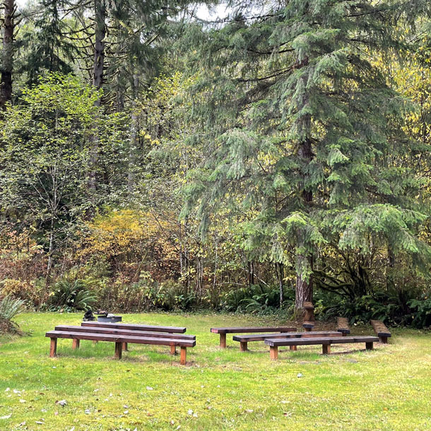 Benches arranged around a fire pit at Girl Scout camp with trees in the background.
