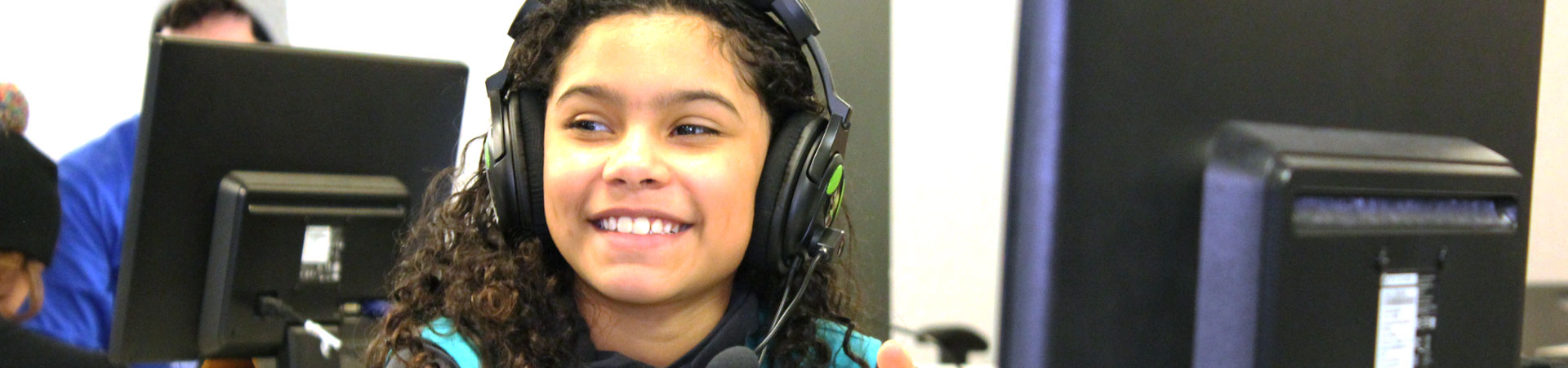  A youth Girl Scout sits at a computer wearing a headset.  