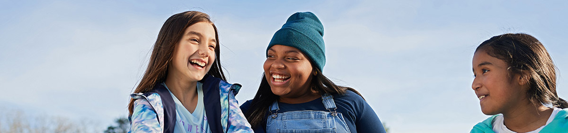  Three older Girl Scouts outside with a blue sky behind them. 