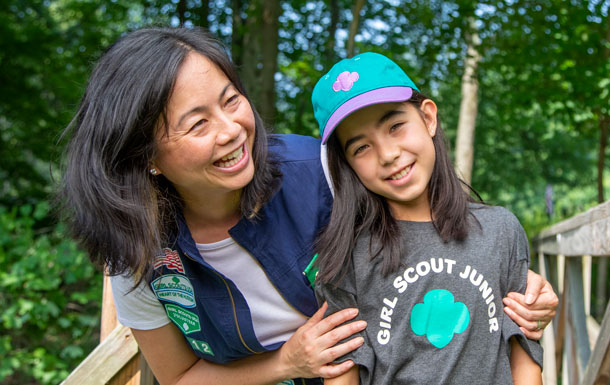 An adult Girl Scout volunteer standing outside with a Girl Scout youth.