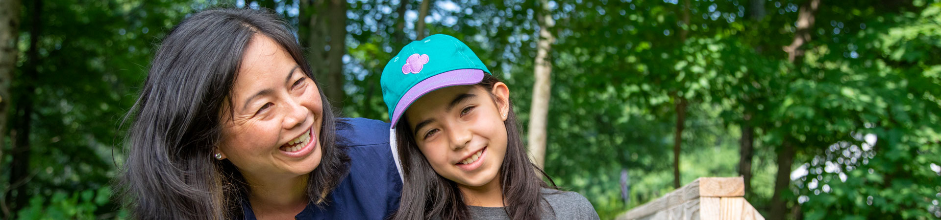  An adult volunteer in a vest outside hugs a Girl Scout while hiking 