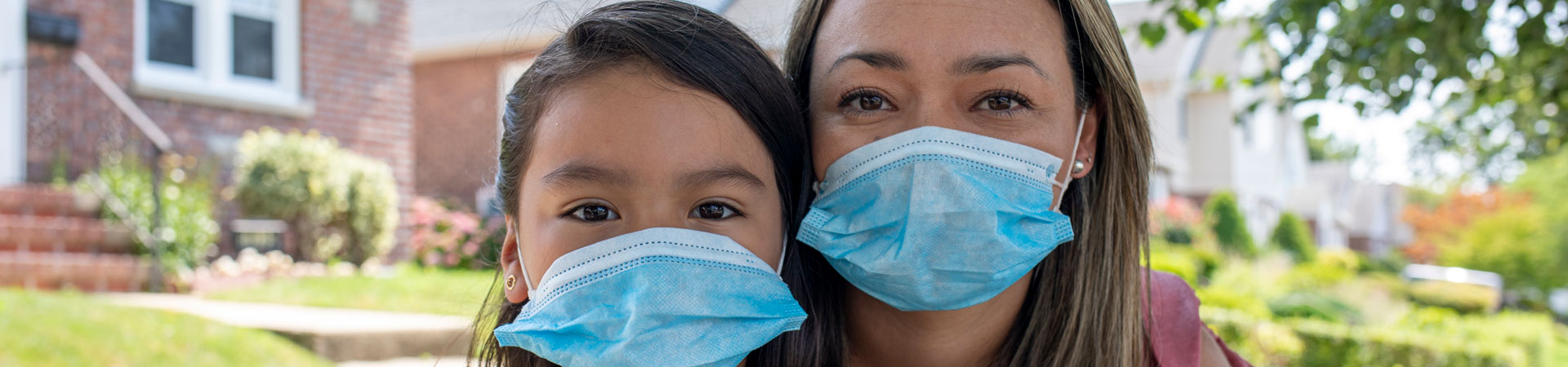  A close up of an adult Girl Scout volunteer youth member standing outside wearing blue surgical face masks. 